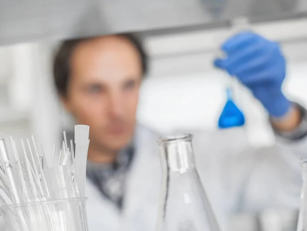 Αρσενικό εργαστήριο ερευνητής εκτελεί δοκιμές με μπλε υγρό — Φωτογραφία Αρχείου
