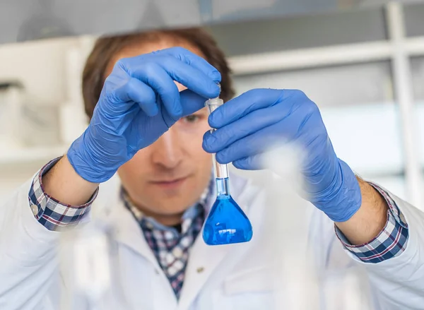 Ricercatore di laboratorio maschile esegue test con liquido blu — Foto Stock