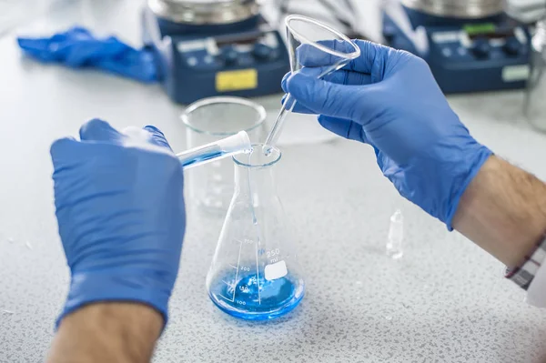 테스트 및 붓는 파란색 액체를 수행 하는 실험실 기술자 — 스톡 사진
