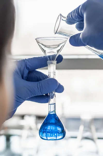 Laboratorium technik wykonuje testy i wlewając płyn niebieski — Zdjęcie stockowe