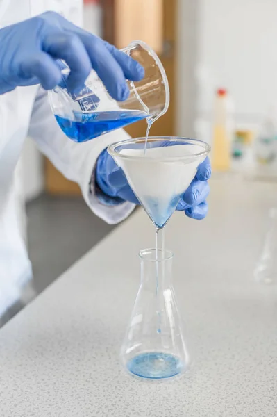 Лаборант проводит тесты и разливает голубую жидкость — стоковое фото