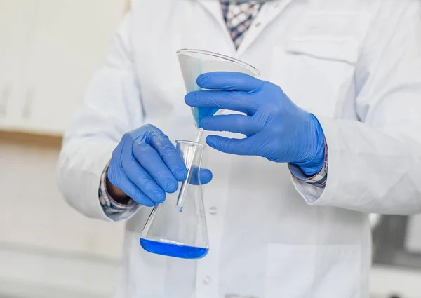 Técnico de laboratorio realiza pruebas y verter líquido azul — Foto de Stock