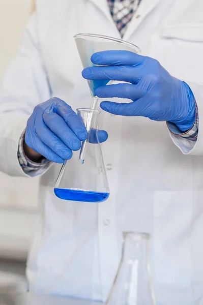 Técnico de laboratório realiza testes e verter líquido azul — Fotografia de Stock