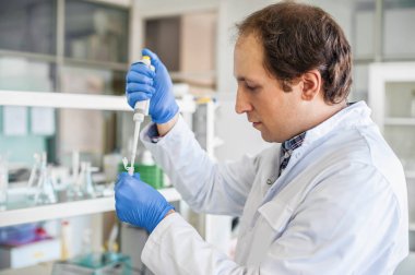 Bilim adamı laboratuvarda test tüpleri pipet ile doldurma