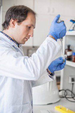 Bilim adamı laboratuvarda test tüpleri pipet ile doldurma