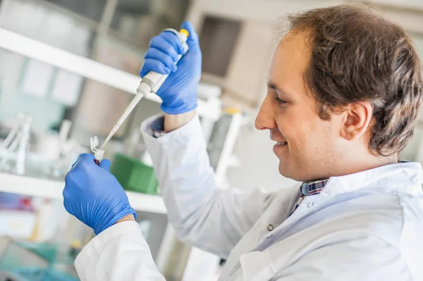 Científico en el laboratorio llenando tubos de ensayo con pipeta —  Fotos de Stock