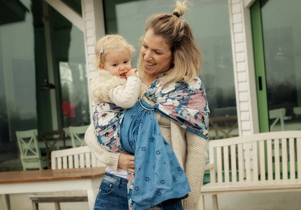 Young mother having her little daughter in baby carrier scarf — Stock Photo, Image