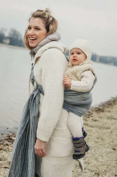 Ung mor med sin lilla dotter i baby carrier halsduk — Stockfoto