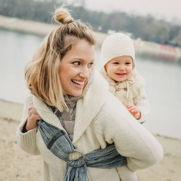 Young mother having her little daughter in baby carrier scarf — Stock Photo, Image