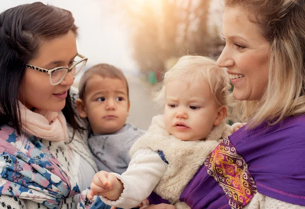 Twee moeders met baby's in draagzakken verdraaien — Stockfoto