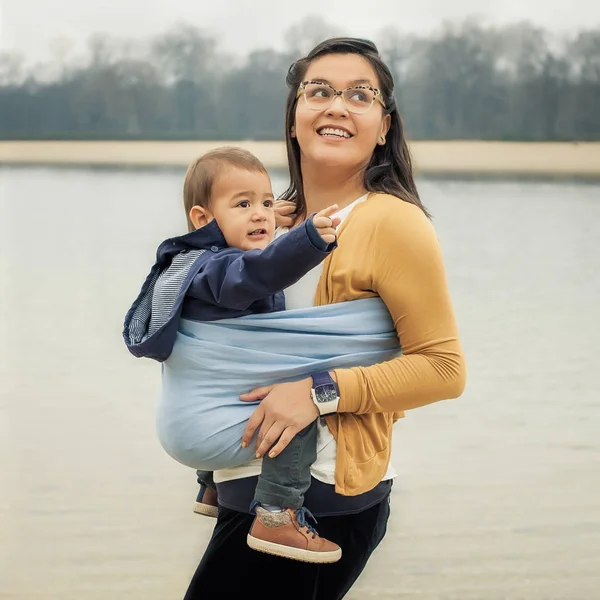 Ung mamma med hennes pojke i en baby carrier halsduk — Stockfoto