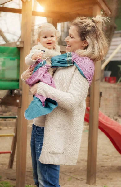 Joven madre teniendo su pequeña hija en pañuelo portabebés —  Fotos de Stock