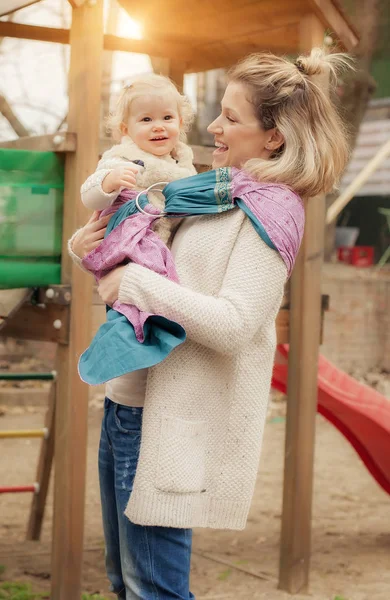 Young mother having her little daughter in baby carrier scarf — Stock Photo, Image