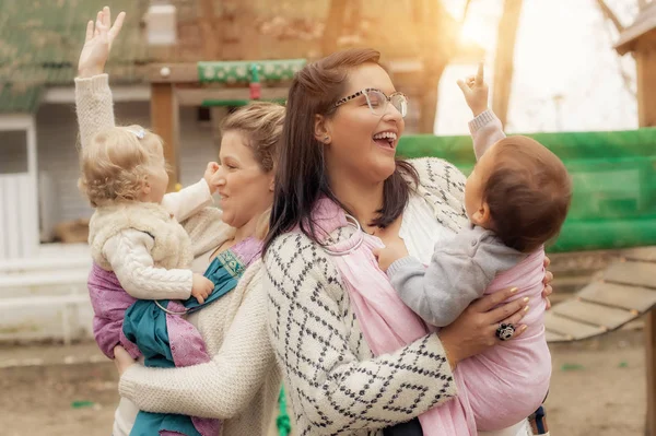 İki anne ile bebek taşıyıcıları bebeklerde çözgü — Stok fotoğraf