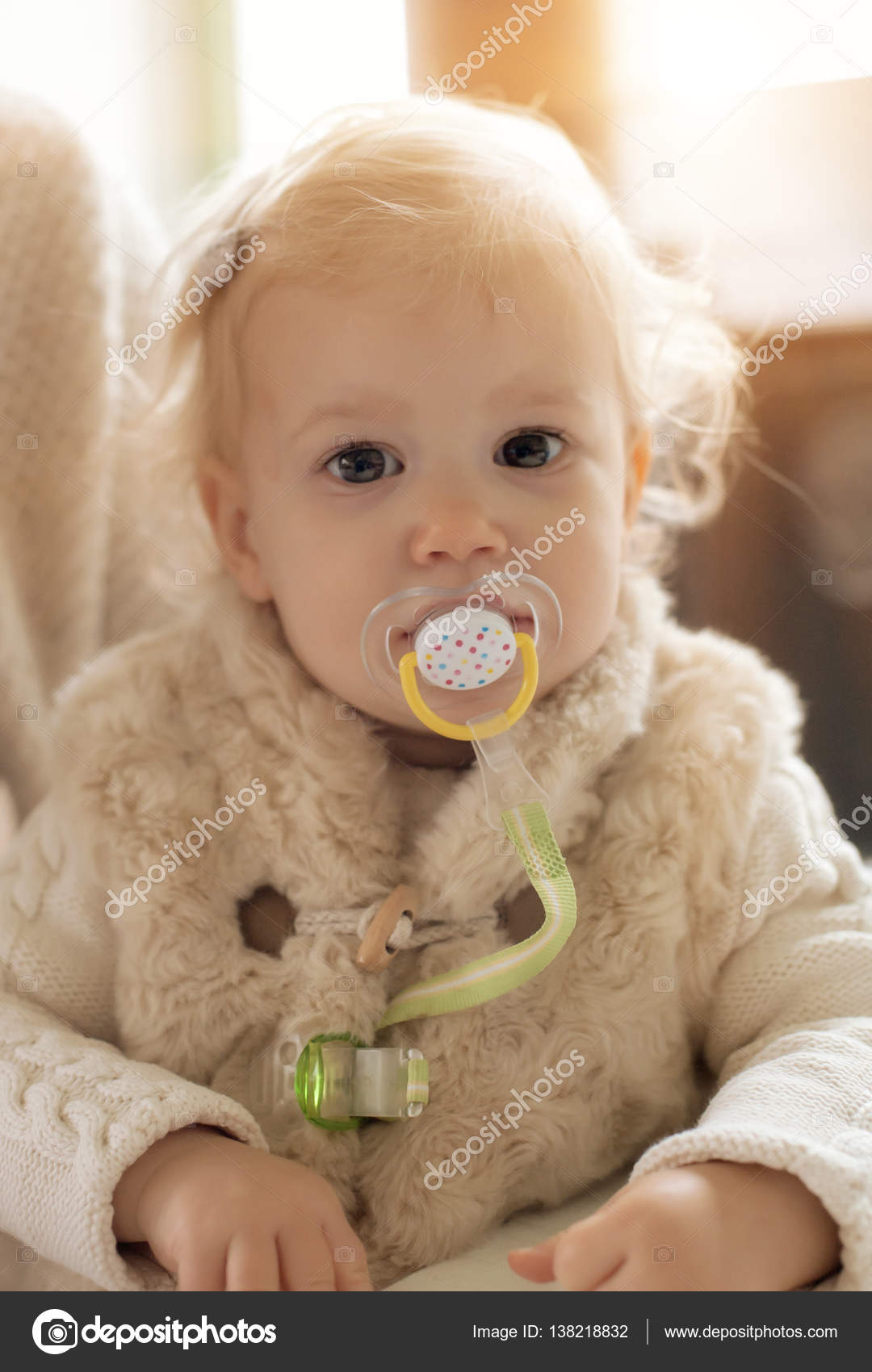 Cute baby girl with a pacifier in her mouth Stock Photo by