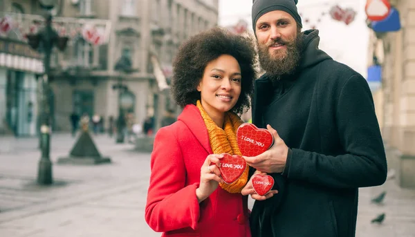 Hermosos jóvenes amantes sosteniendo un tres corazones rojos — Foto de Stock