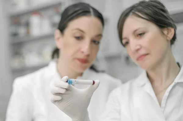 Dos científicos sosteniendo un tubo de ensayo con muestra — Foto de Stock