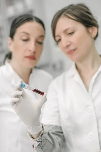 Dos científicos sosteniendo un tubo de ensayo con muestra — Foto de Stock