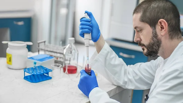 Scientist filling test tubes with pipette in laboratory — Stock Photo, Image