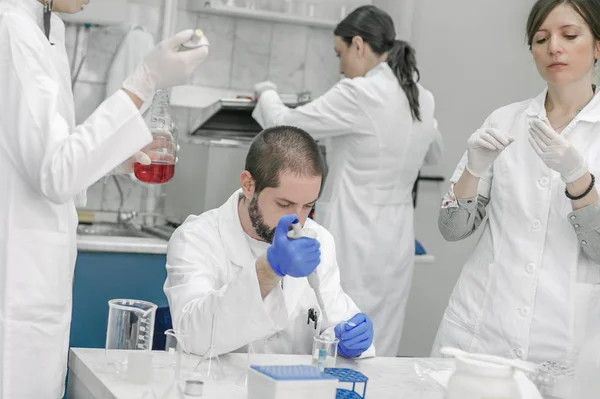 Grupo de científicos que trabajan con muestras de tubos de ensayo líquidos — Foto de Stock