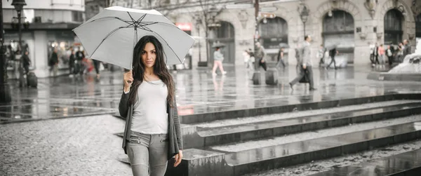 Donna con un ombrello sotto pioggia su una strada di città — Foto Stock