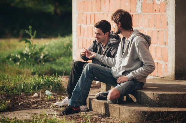 Two friends smoking joint in abandoned ghetto part of city — Stock Photo, Image