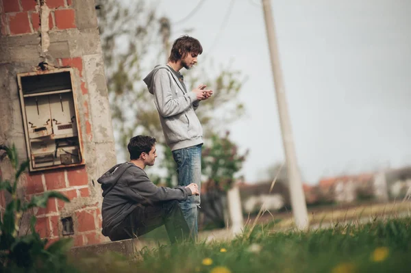 Two friends smoking joint in abandoned ghetto part of city — Stock Photo, Image