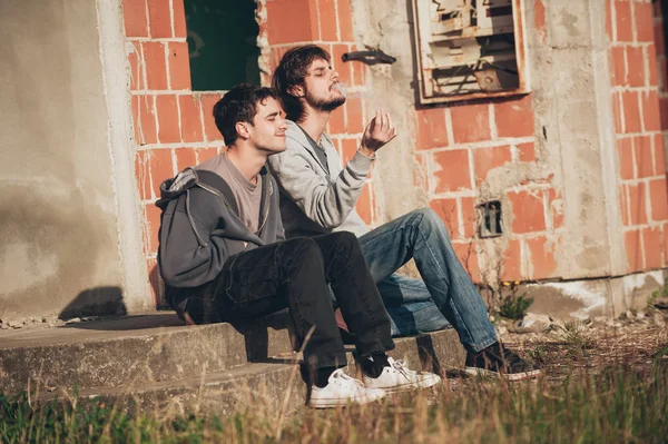 Dois amigos fumando charro no gueto abandonado parte da cidade — Fotografia de Stock