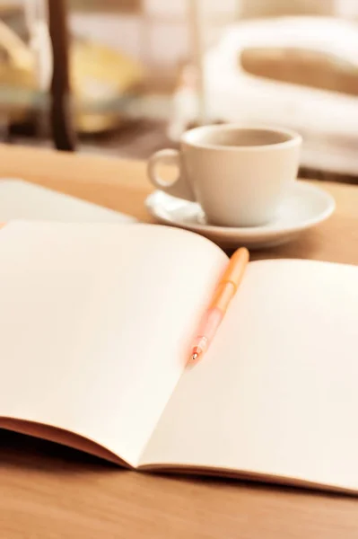 Taza de café, cuaderno y bolígrafo en la mesa de madera — Foto de Stock