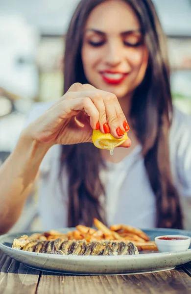 여자는 식당에서 생선의 부분에 레몬을 짜 내 — 스톡 사진