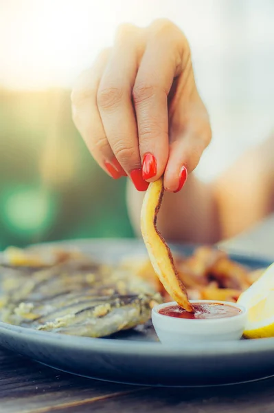 Mujer comiendo papas fritas con ketchup en un restaurante — Foto de Stock