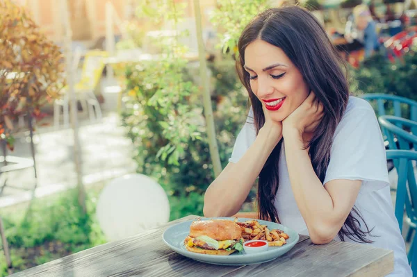 Щаслива молода жінка їсть смачно фастфуд бургер — стокове фото