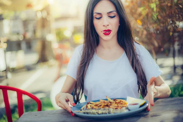 Mujer joven comiendo pescado fresco sabroso con papas fritas — Foto de Stock