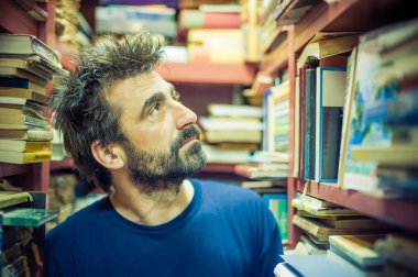 Meraklı adam kitap kütüphane rafları arasında seçme