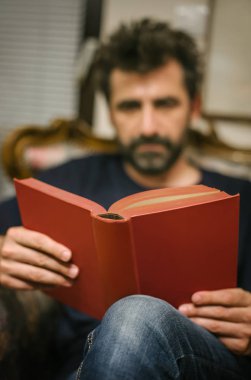 Adam evde vintage sandalyede otururken kitap okuma