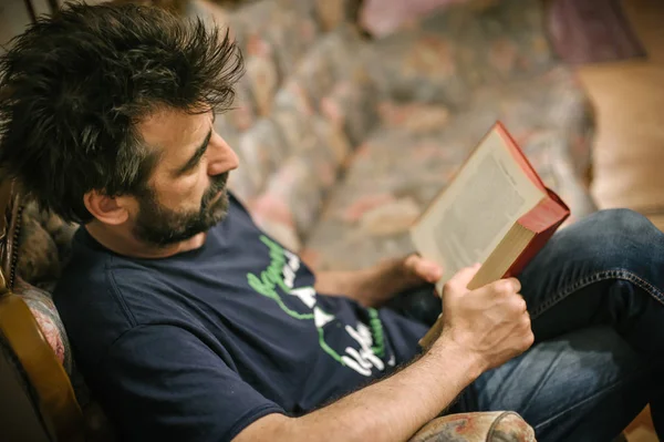 Człowiek, czytanie książki, siedząc w fotelu vintage w domu — Zdjęcie stockowe