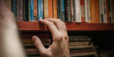 Meraklı adam onun kitaplığında evde kitap seçimi