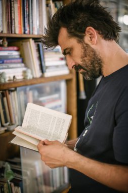 Meraklı adam onun kitaplığında evde kitap seçimi