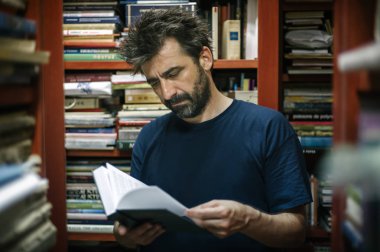 Meraklı adam onun kitaplığında evde kitap seçimi