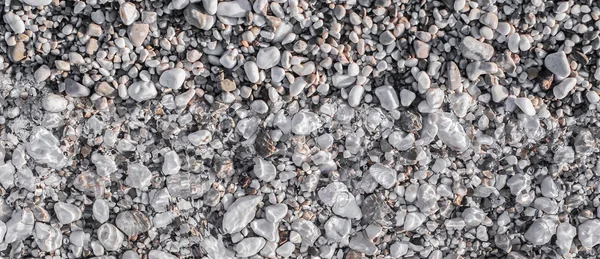 Guijarros de mar en la playa bajo una capa de agua transparente — Foto de Stock