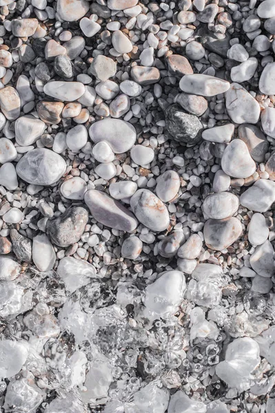 Guijarros de mar en la playa bajo una capa de agua transparente — Foto de Stock