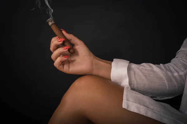 Fechar-se de mão mulher detém tompus cigare em sua perna nua — Fotografia de Stock