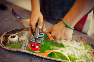 Genç adam onun kaykay üzerinde tekerlek sabitleme doğrama Atölyesi