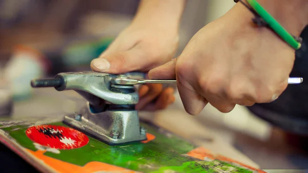 Joven en taller de carpintería fijando rueda en su monopatín —  Fotos de Stock