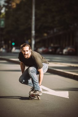 Kaykaycı binmek bir kaykay yamaç şehrin içinden sokak