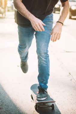 Kaykaycı bacakları sokakta kaykay sürüyor.