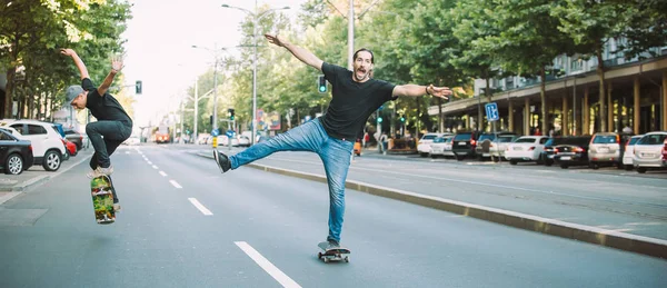 Twee gelukkige en grappige schaatsers rijden skateboard stad straat — Stockfoto