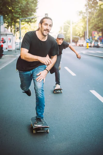 İki kaykay kaykay yamaç şehir sokaklarda sürme