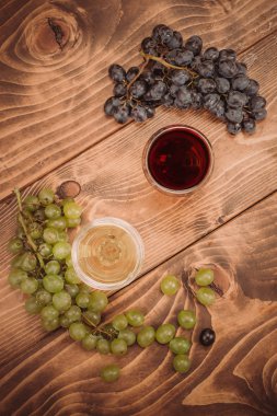 Kırmızı ve beyaz şarap, gözlük ve ahşap masa üzüm