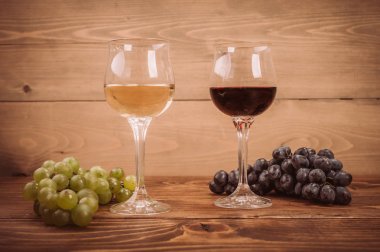 Kırmızı ve beyaz şarap, gözlük ve ahşap masa üzüm